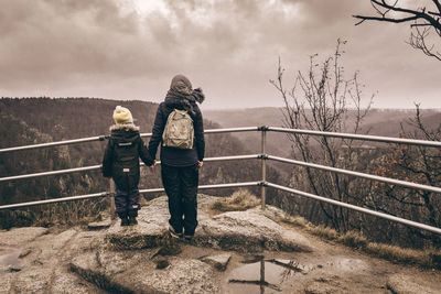 Rear view of people standing at observation point against sky