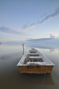 Boat moored in sea against sky during sunset