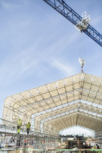 Workers working at construction site against sky