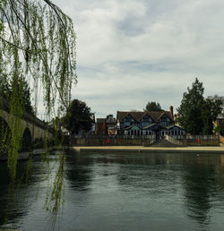 Bridge over river by buildings against sky