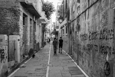 Rear view of people walking on street amidst buildings