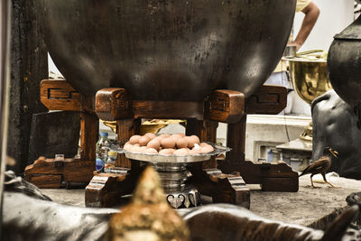 Eggs as a donation under a giant wooden cauldron like pot at the grand palace