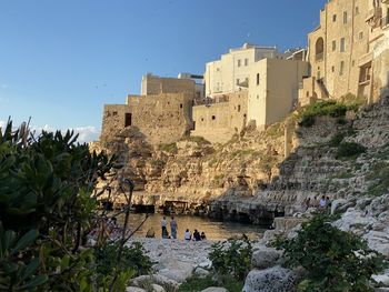 People at historic building against clear sky