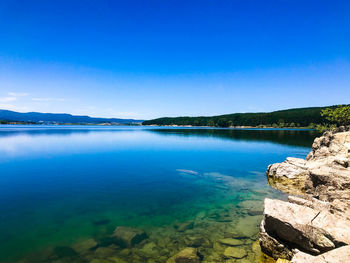 Scenic view of lake against clear blue sky