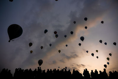 Low angle view of silhouette people flying against sky