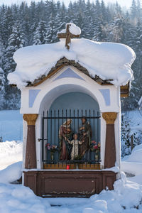 The mountain chapel with cross covered with wooden shingle. snow-capped mountains, trees.