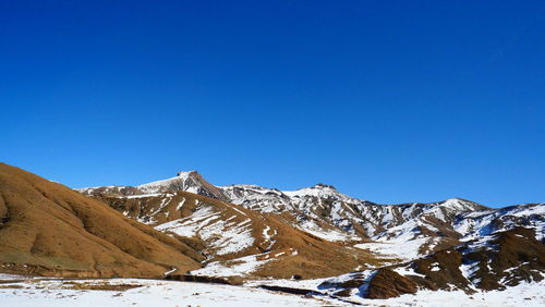 Scenic view of snowcapped mountains against clear blue sky