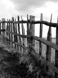 Wooden posts in sea against sky