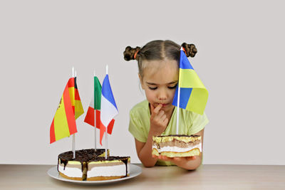 Girl holds baked cake with several european flag and ukrainian one also. europe and euro integration