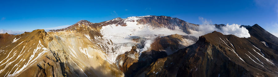 Panoramic view of snowcapped mountains against blue sky