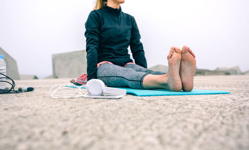 Low section of woman sitting on floor against sky