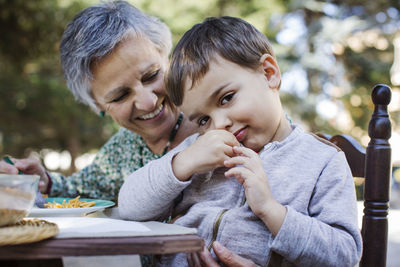 Portrait of cute boy sitting with grandmother at outdoor table
