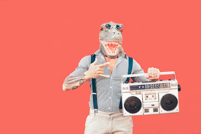 Man wearing mask while holding radio against red background