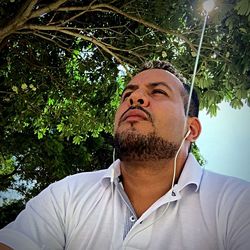 Portrait of young man against tree