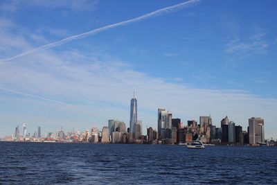 Sea by modern buildings in city against sky