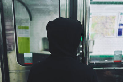 Rear view of man looking through train window