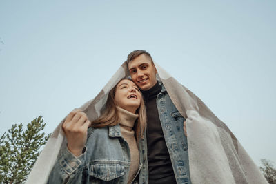 Young couple underhome-shaped blanket, unique concept for mortgage