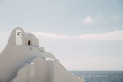 Lighthouse by sea against clear sky