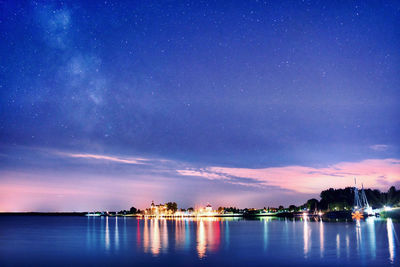 Scenic view of illuminated sea against sky at night