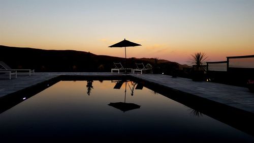 Silhouette swimming pool against sky during sunset