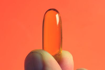 Close-up of human hand against orange background