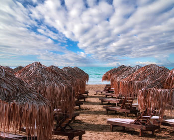 Public sand beach with palm leaves tents under dranatic summer sky in cyprus larnaca