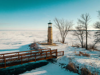 The lake is frozen with a blue sky but this old abandoned lighthouse stands watch over the water.