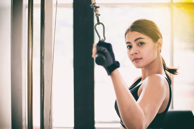 Side view portrait of confident young woman exercising in gym