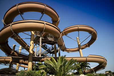 Low angle view of the slide at a water park against clear blue sky 