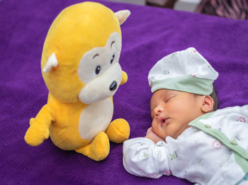 Newborn baby isolated sleeping in white cloth with teddy and purple background from different angle