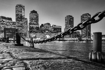 Bollards at harbor against illuminated city during night