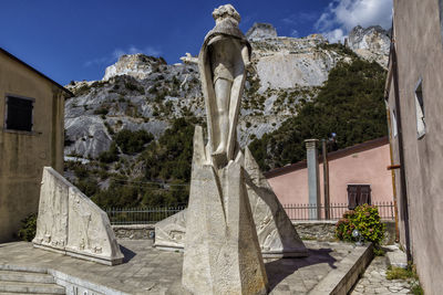 Statue amidst trees and buildings against sky