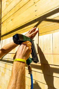 Low angle view of hand holding umbrella against wooden wall