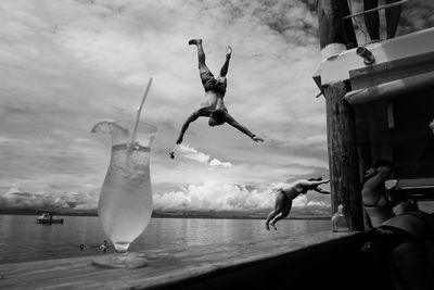 Man jumping over sea against sky