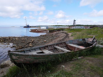 Abandoned boats moored at shore against sky