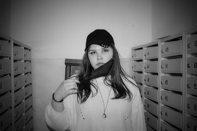 Portrait of young woman standing against wall