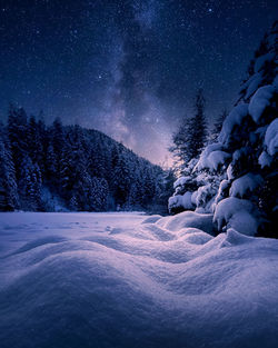 Snow covered landscape against sky at night