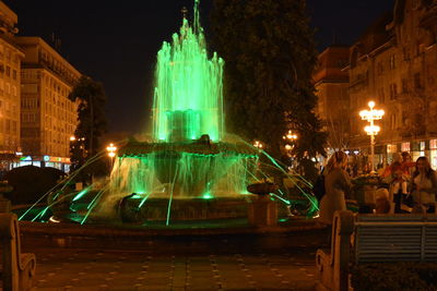 Illuminated fountain in city at night