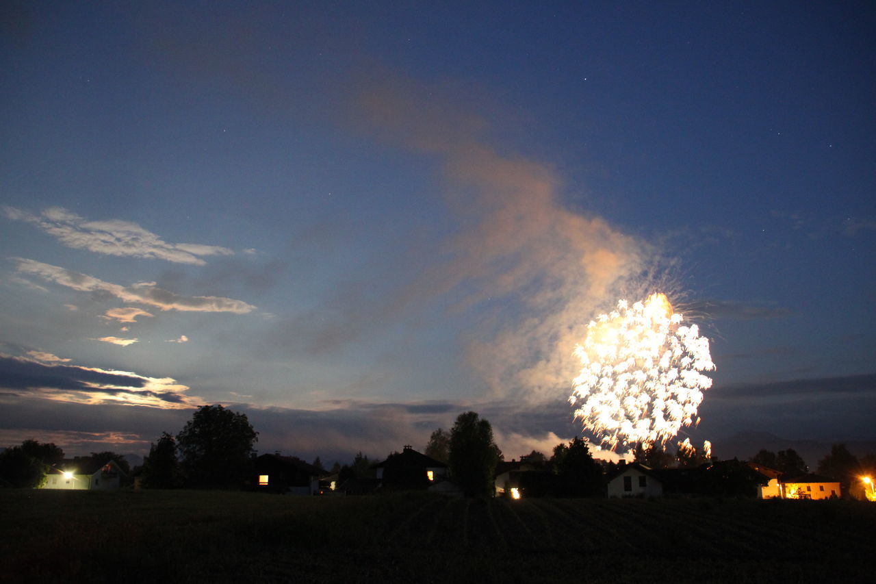 FIREWORK DISPLAY OVER SILHOUETTE FIELD AGAINST SKY AT SUNSET