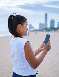 Side view of young woman drinking water at beach