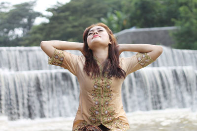 Low section of young woman standing in front of water