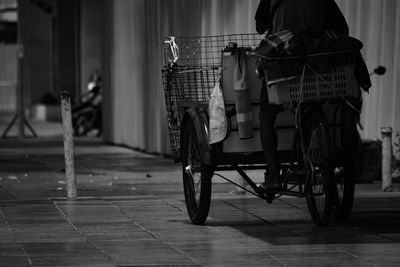 Low section of man riding bicycle cart on footpath