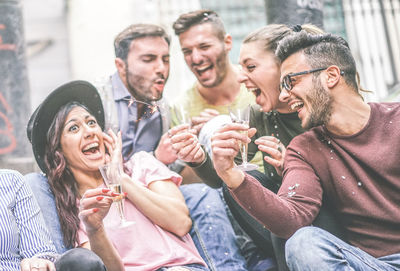 Cheerful male and female friends enjoying party during sunny day