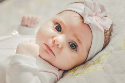 High angle portrait of cute baby girl lying on bed at home