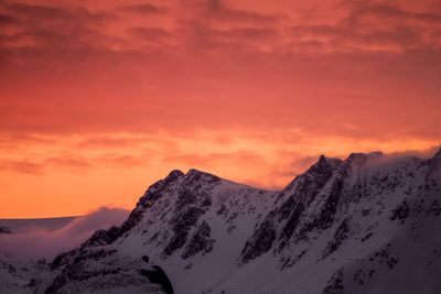 Scenic view of snowcapped mountains against orange sky