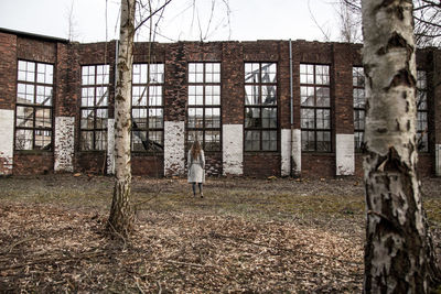 Rear view of woman standing against abandoned building