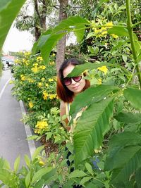 Portrait of young woman standing by plants