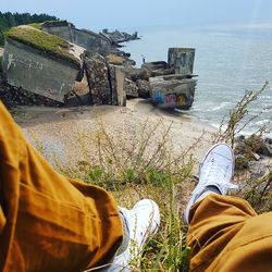 Low section of man standing by sea