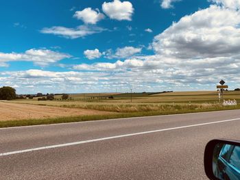 Road passing through landscape against cloudy sky