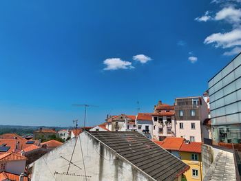 High angle view of buildings in city against blue sky